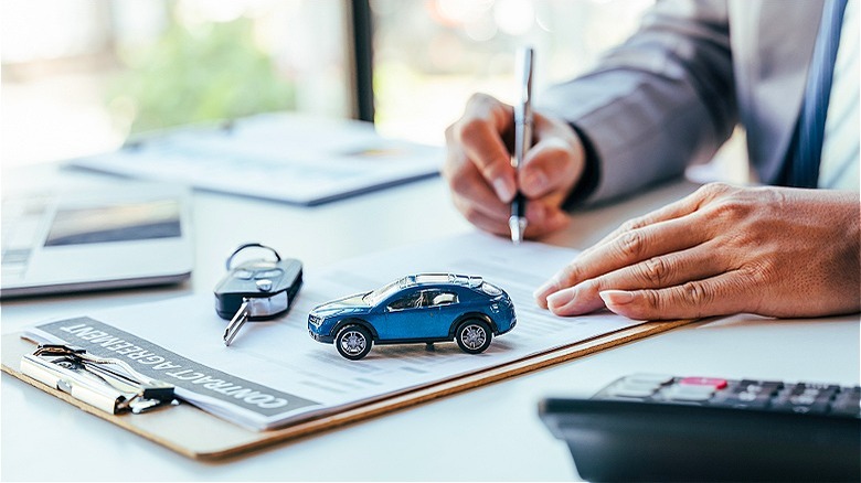 Person signing car dealership paperwork
