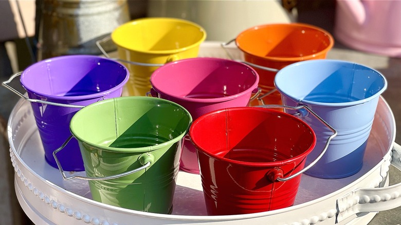 A tray of purple, mustard, green, pink, red, orange, and baby blue buckets