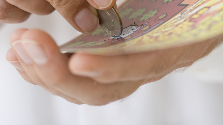 Man's hand scratching off lottery ticket in America,