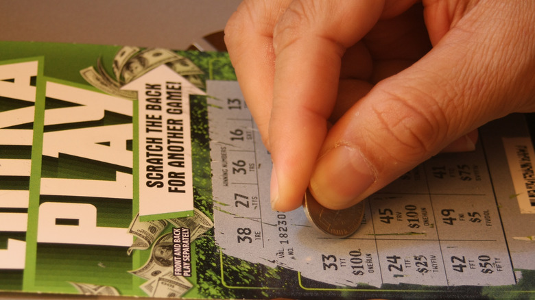 Man's hand scratching off lottery ticket in America,