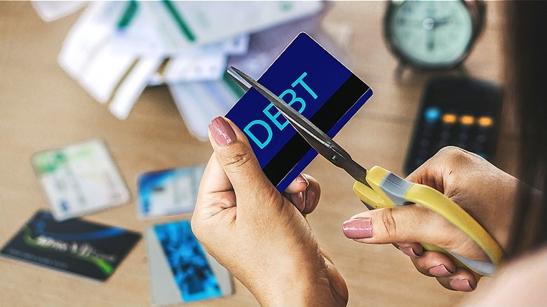 Person cutting up "DEBT" card