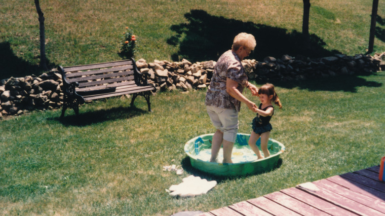 woman playing in kiddie pool with her granddaughter