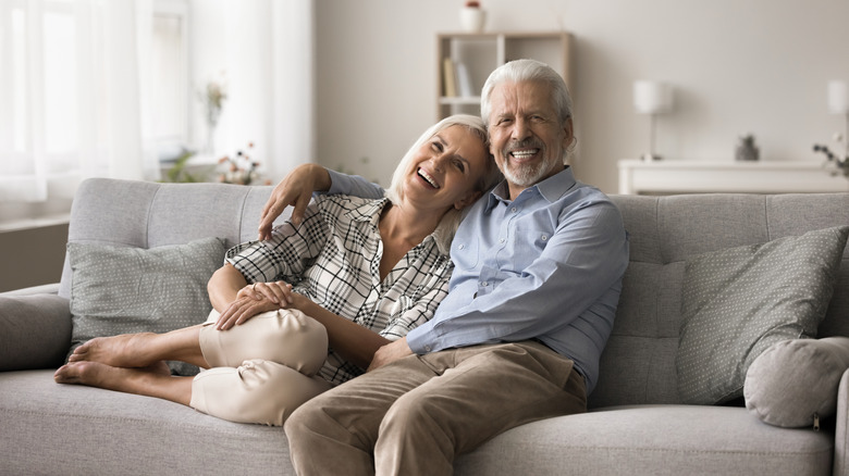 Mature couple sitting on sofa smiling