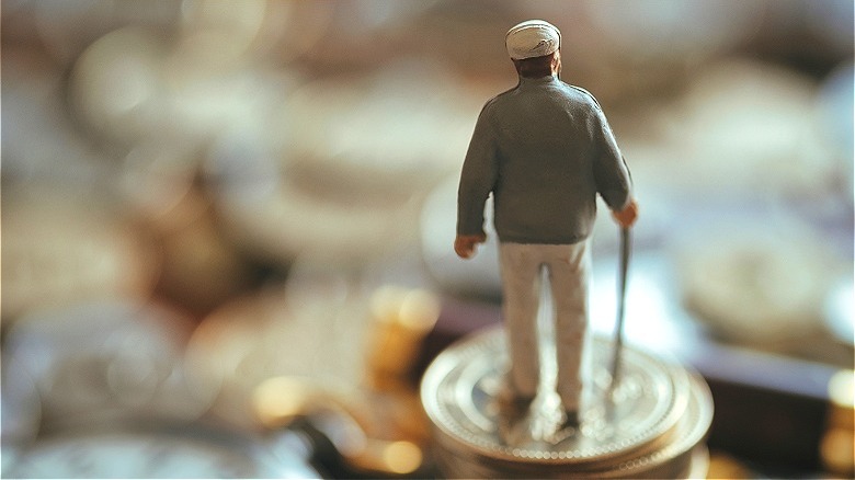 Person figurine standing on coins