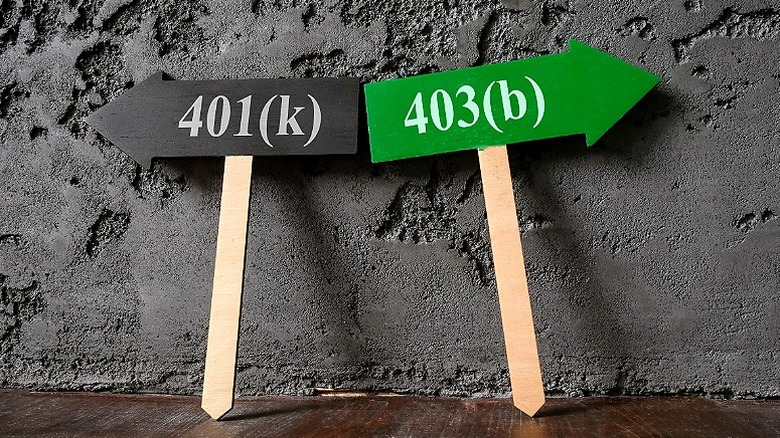 Two wooden stakes with opposing arrows, one reads 401(k) and the other 403(b)