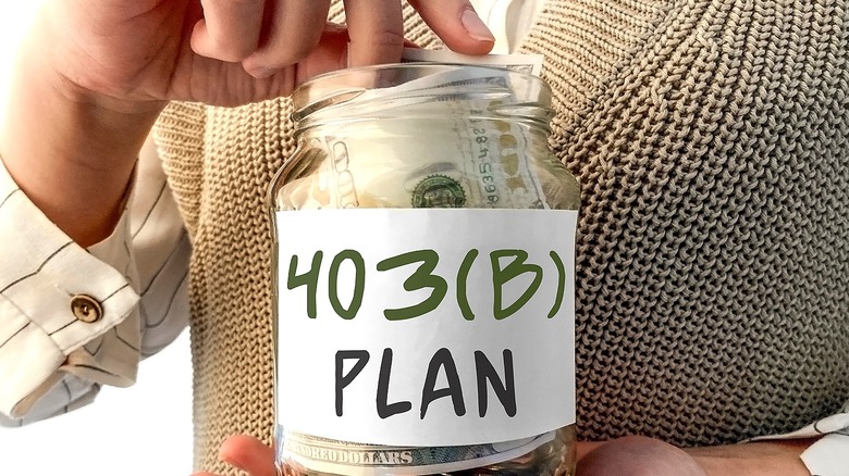 A person adds money to glass jar labeled 403(b) plan