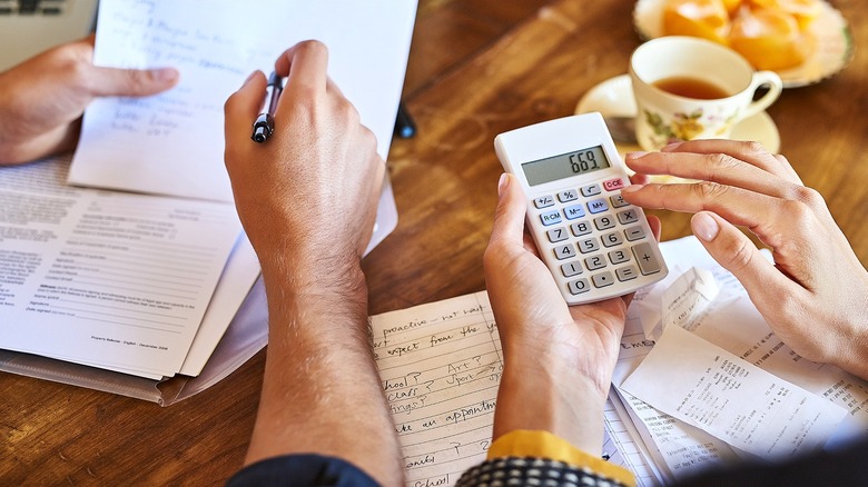 Going over numbers with pen, paper, and a calculator while having tea