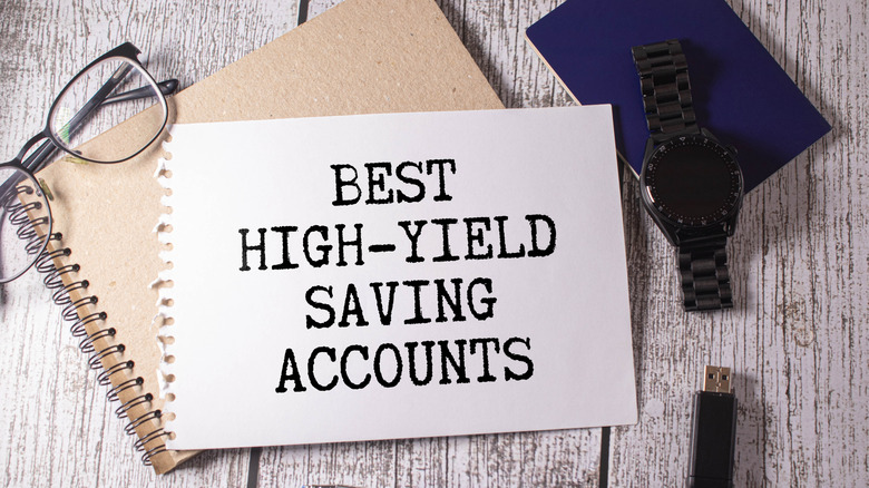 Best high-yield saving accounts written on spiral notebook with glasses, watch, and thumb drive aside