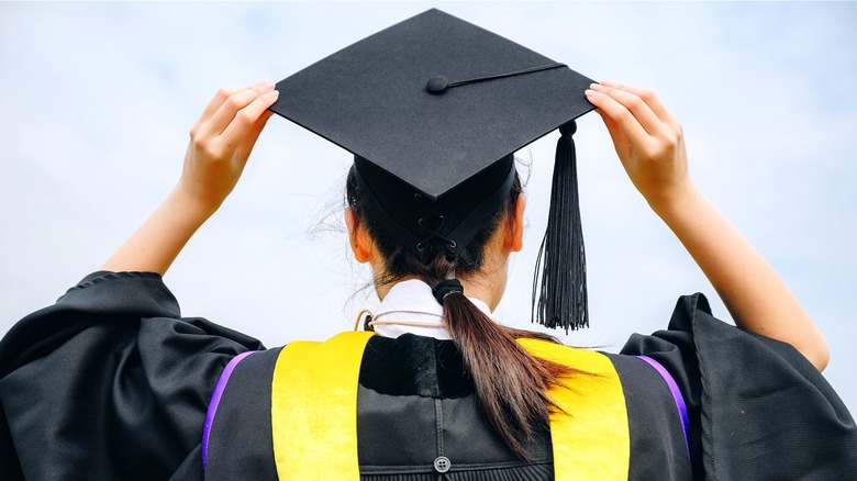 Graduate facing backward holding cap