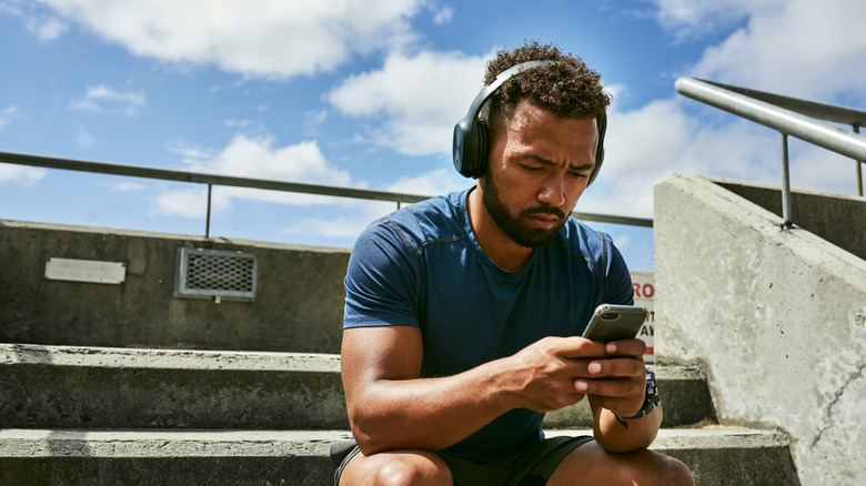 Man sitting down on his phone with headphones on