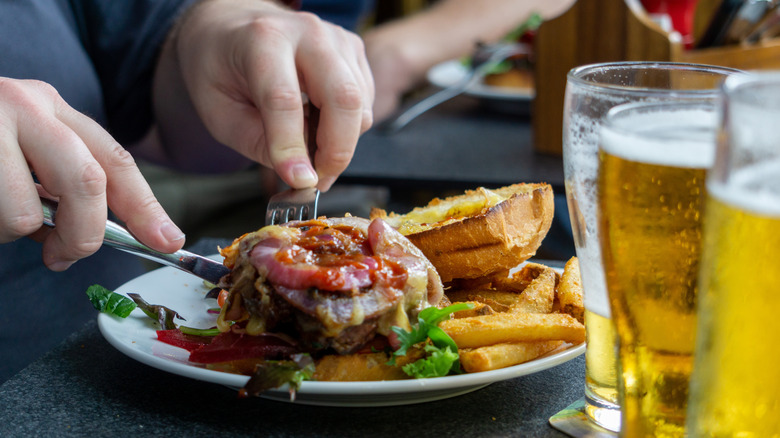 A man carving up a cheeseburger