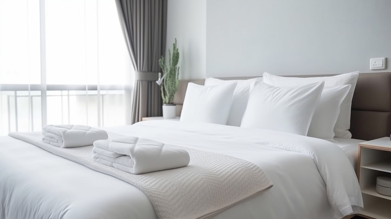 A hotel bed with beautifully white sheets and fluffed pillows.