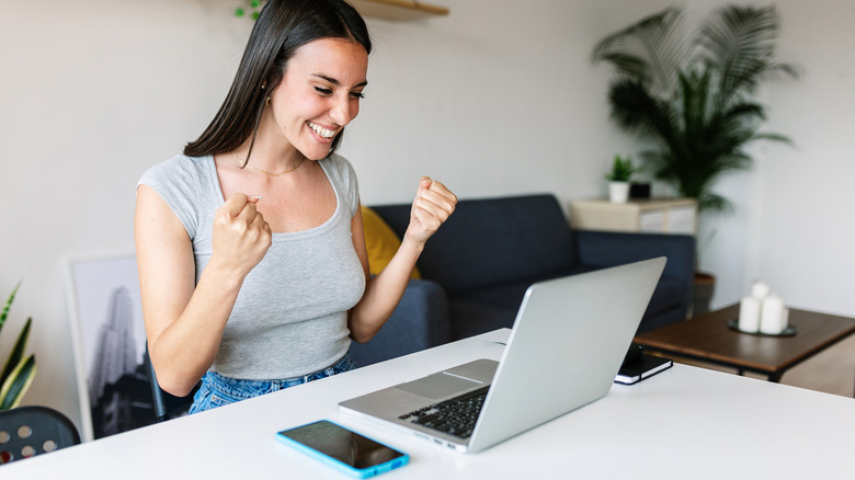 young woman at computer reacting happily