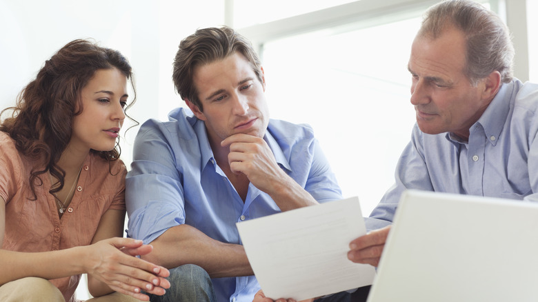 man explaining financial document to a younger couple