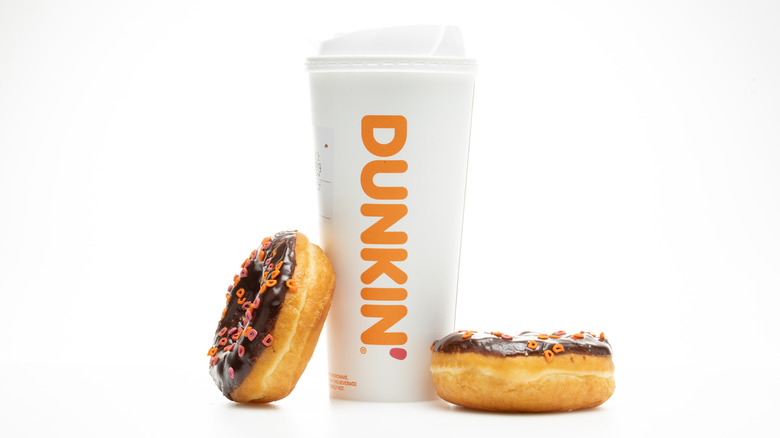 A large hot Dunkin' Donuts coffee, flanked by two sprinkle donuts.