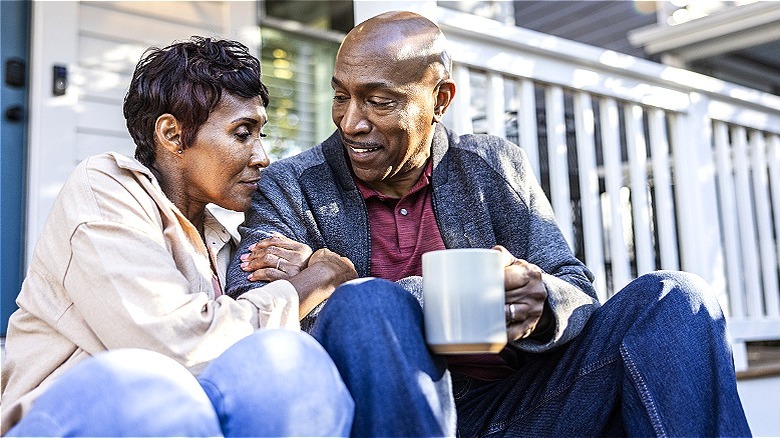 Married couple sits on porch steps together smiling