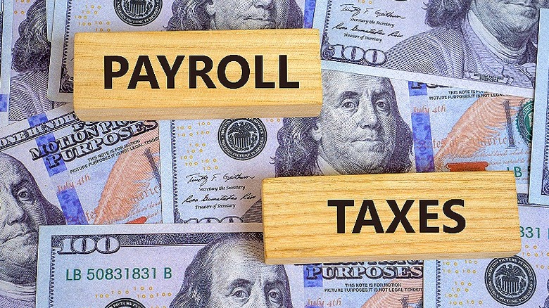 Wooden blocks with the words 'payroll' and 'taxes' sit on $100 bills