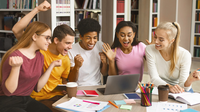 A celebratory group of Gen Zers looking at a laptop screen