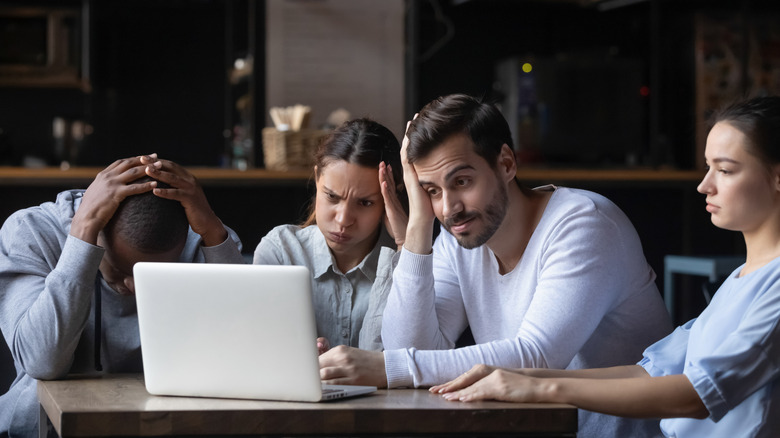 A group of depressed looking Gen Zers staring at a laptop screen