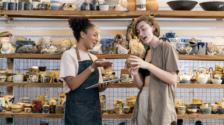 Woman buying craft product from owner in store