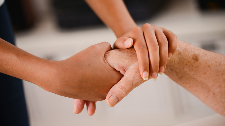 A young person holds an elderly person's hand