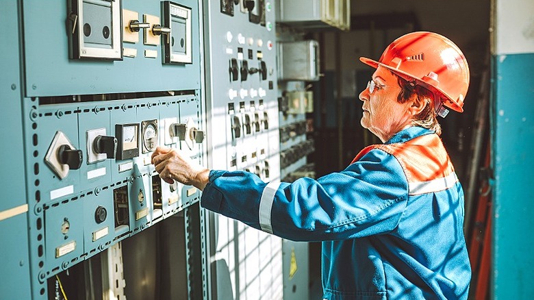 An older worker wearing a hard hat while working on electrical equipment