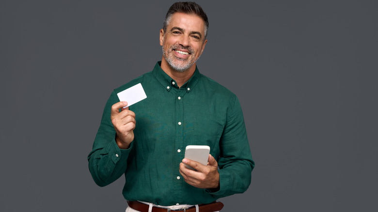 Happy man holds credit card for his mobile phone crypto purchase