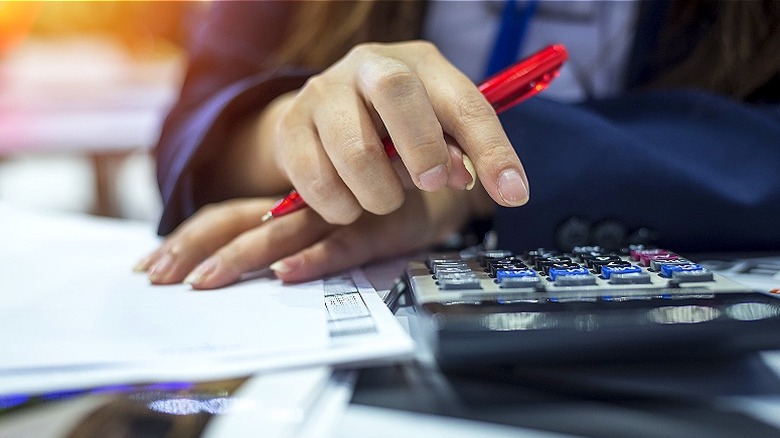 Person holding pen, calculating expenses