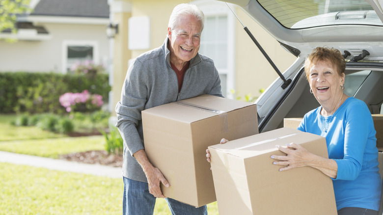 Happy senior couple carry moving boxes