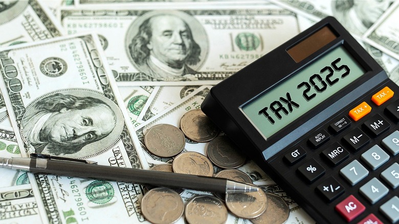 Pen next to calculator with 'Tax 2025' in display and both on top of $100 bills