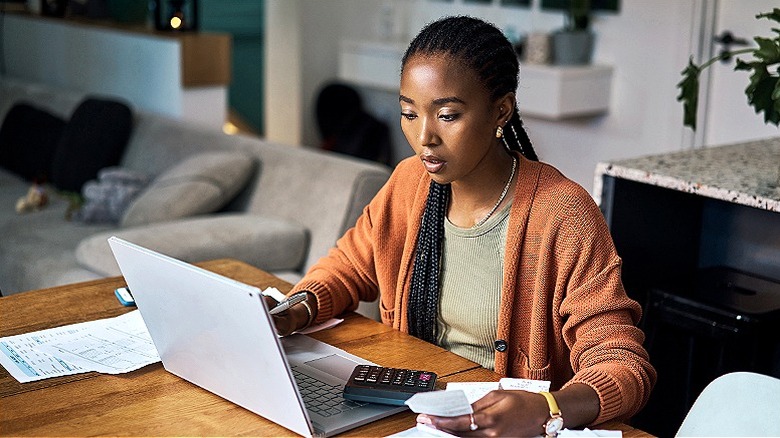 Woman working paying bills on laptop computer at home