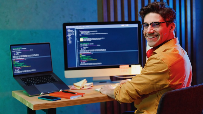 A man smiling in front of two laptops