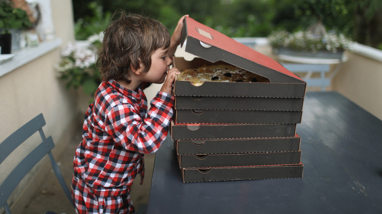 A child looking into a box of pizza