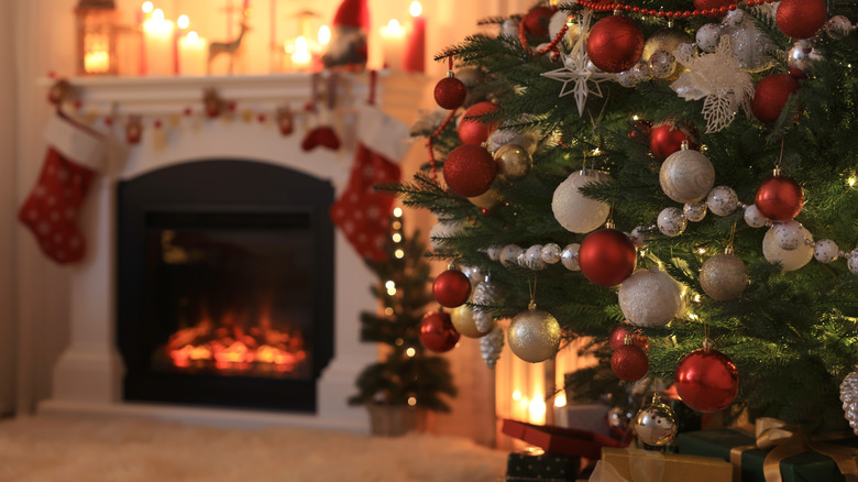 Decorated Christmas tree stands before fireplace