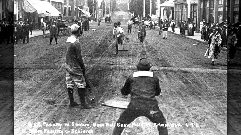 Vintage real-photo postcard of a street baseball game