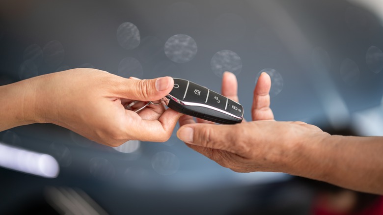 Action of human hands are giving and taking a car key.