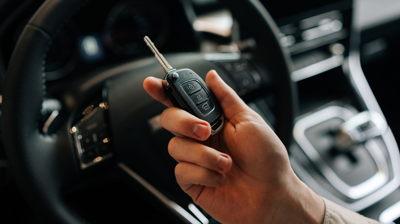 A driver holding key to new car in hand.