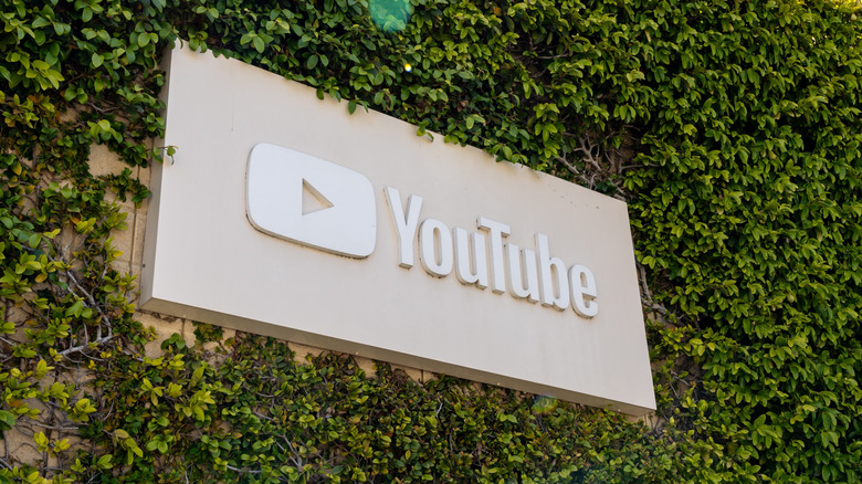 A shot of the YouTube sign, surrounded by greenery, at YouTube headquarters in California.