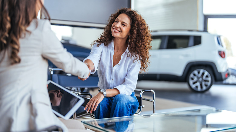 Woman buying a car and closing the deal with a handshake with the saleswoman