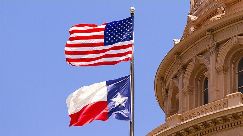 U.S. and Texas state flag flying above Texas Capitol building