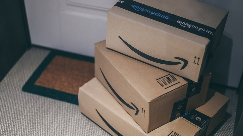 A stack of Amazon Prime delivery boxes on a doorstep welcome mat.