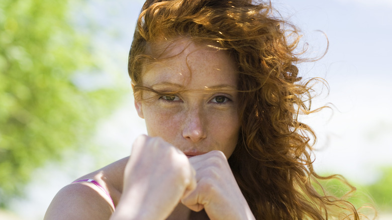 A woman hodling both hands in fists in front of her face in a fighting pose.