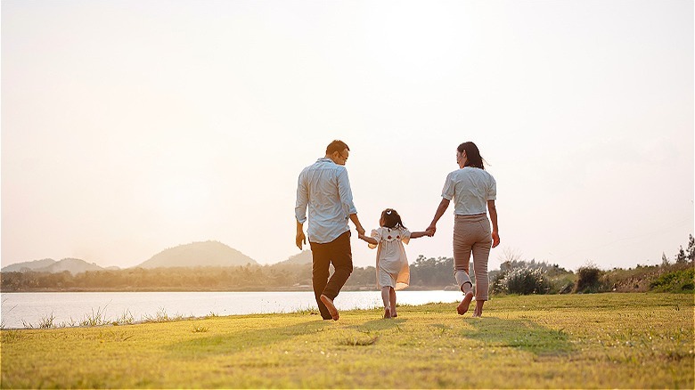 Family walking in sunlit park