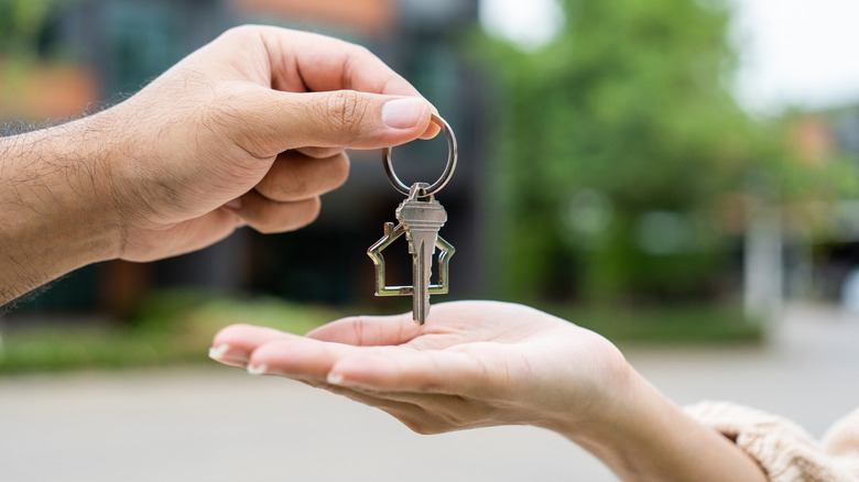 A set of housekeys being handed from one hand to another.