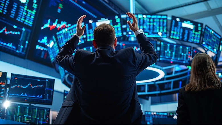 A trader on the trading floor with hands up looking at monitors