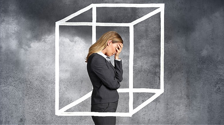 Woman seen with her head in her hand while inside of a box drawing