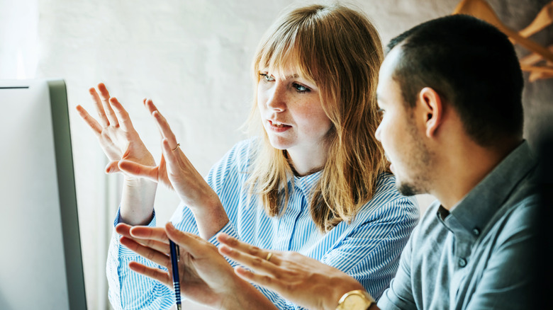 Two people having a discussion in front of a computer monitor