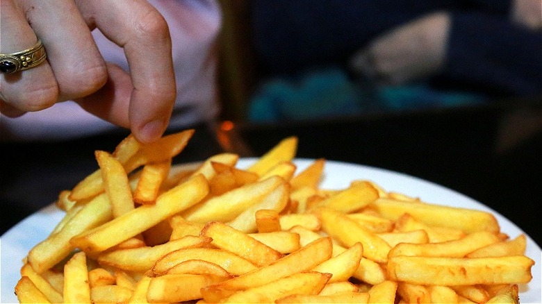 Hand taking fry from plate