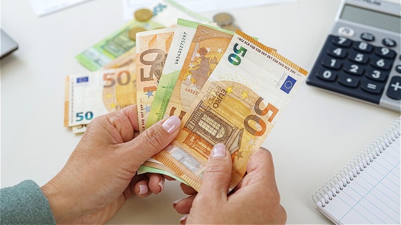 Person counting euros at desk