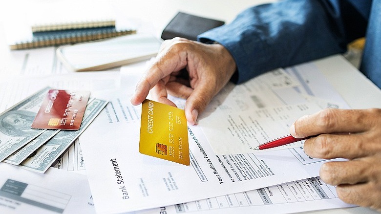 Person reviewing bank statement while holding credit card